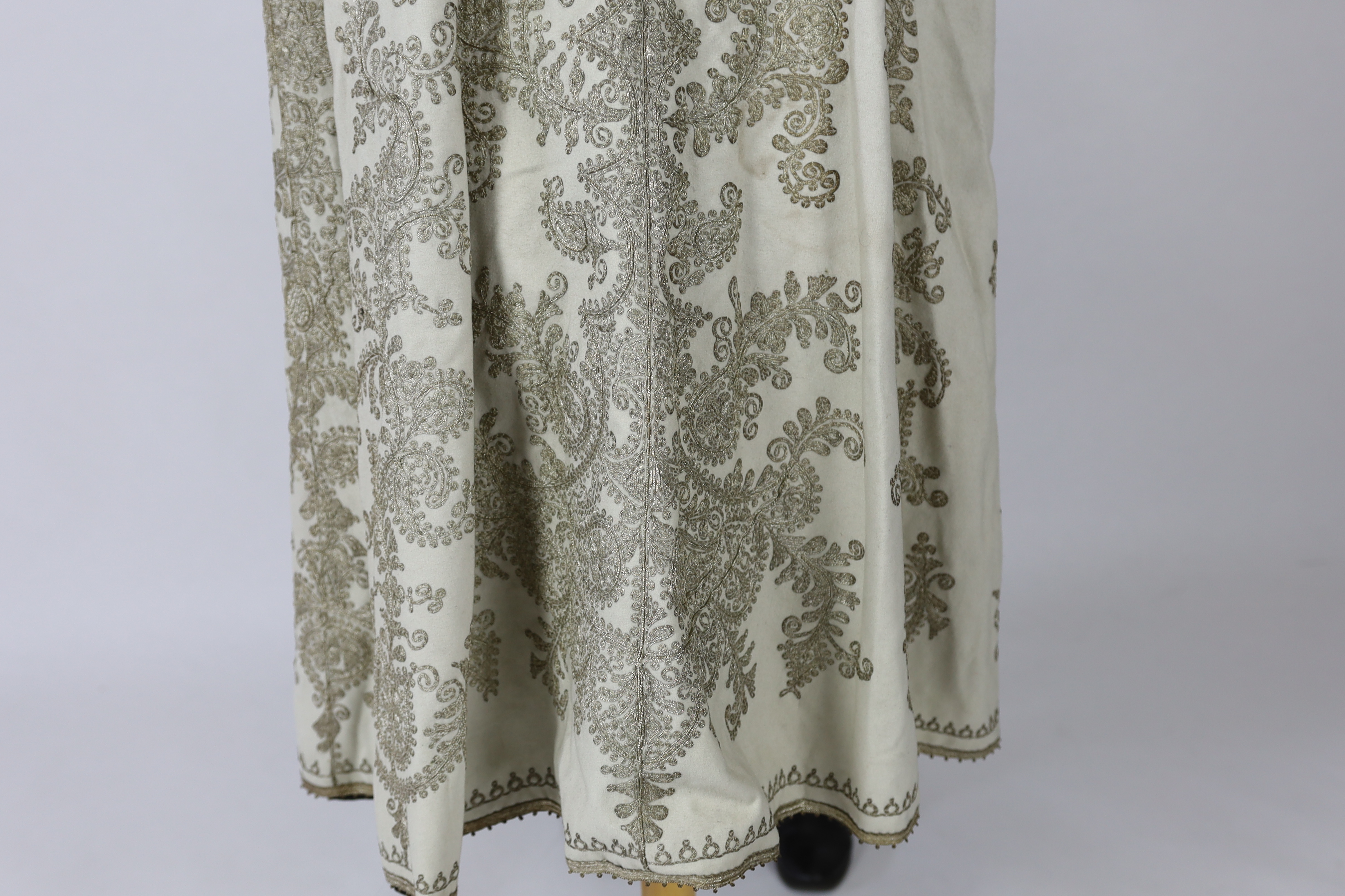 A 19th century Indian fine cream wool embroidered cape, probably made for the European market, embroidered in panels of silver metallic thread in an ornate vertical design with turquoise embellishments and lined in black